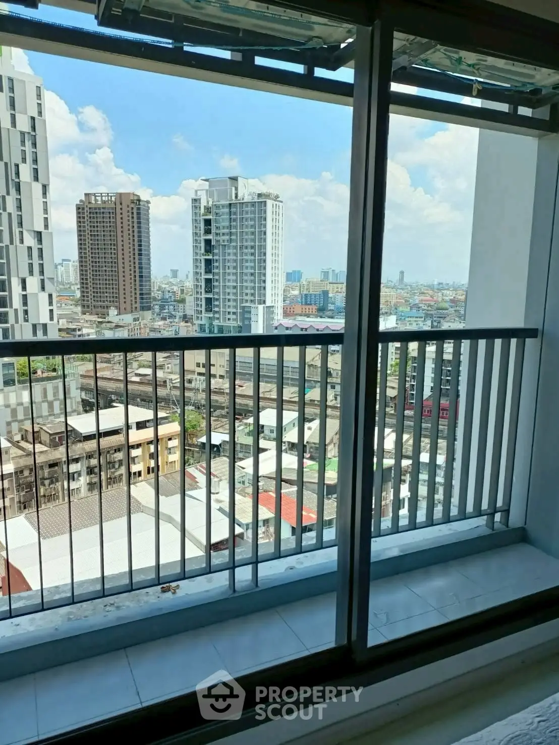 Stunning city view from a high-rise balcony with modern railing and clear blue sky.