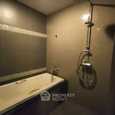 Modern bathroom with sleek bathtub and rainfall showerhead, perfect for relaxation.
