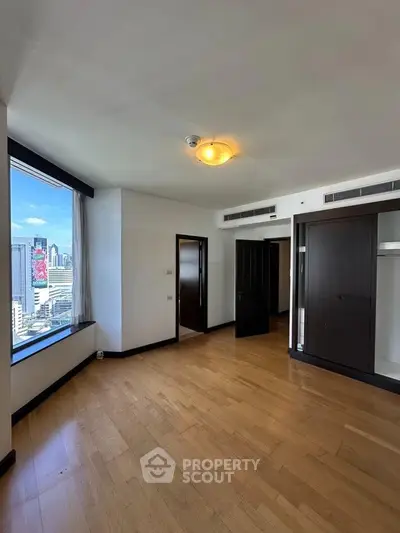 Spacious bedroom with city view and wooden flooring