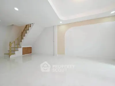 Spacious modern living room with elegant staircase and minimalist design.