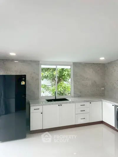 Modern kitchen with sleek white cabinets and large window view