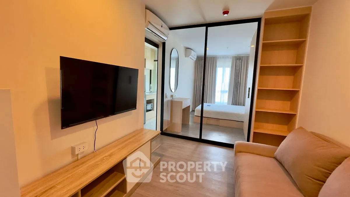 Modern apartment with open living room and bedroom, featuring sleek design and natural light.