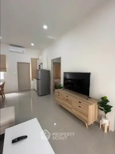 Modern living room with sleek furniture and open layout, featuring a large TV and stylish decor.
