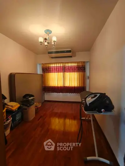 Cozy room with wooden flooring, air conditioning, and ironing board, ideal for versatile use.
