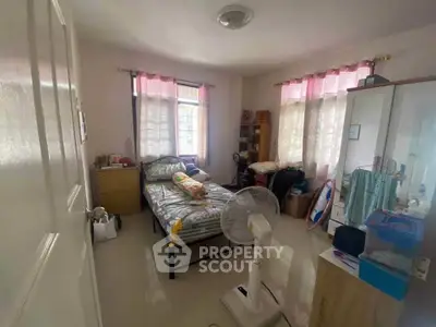 Cozy bedroom with natural light, featuring a single bed, wardrobe, and fan, ideal for comfortable living.