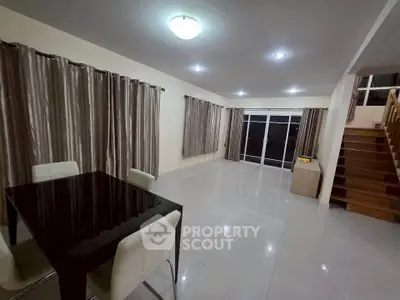 Spacious modern living room with elegant dining area and staircase, perfect for family gatherings.