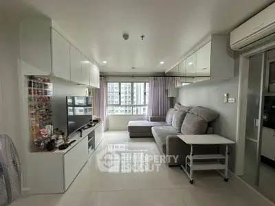 Modern living room with sleek furniture and large window offering city view.