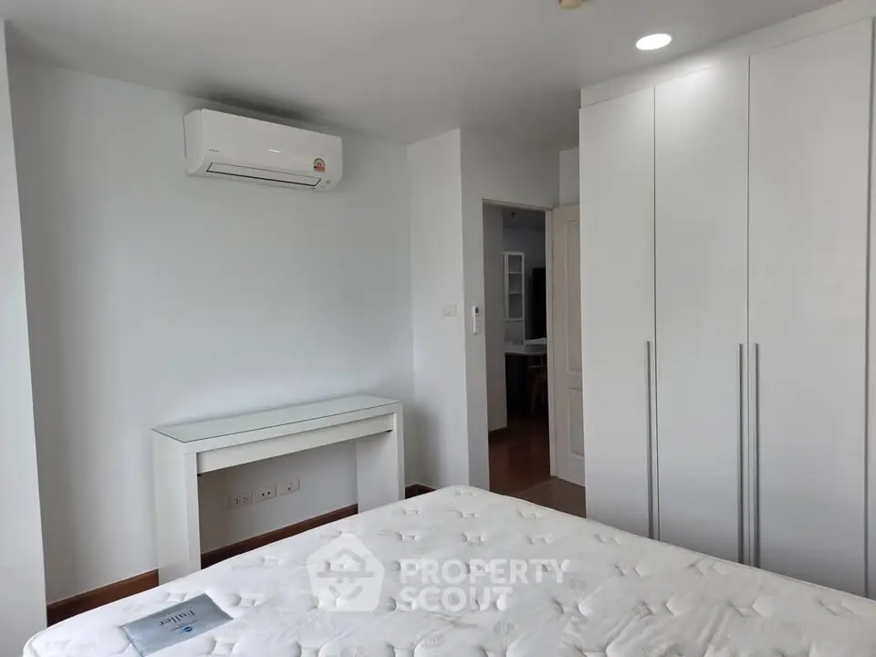 Modern bedroom with air conditioning and built-in wardrobe, featuring a minimalist design.