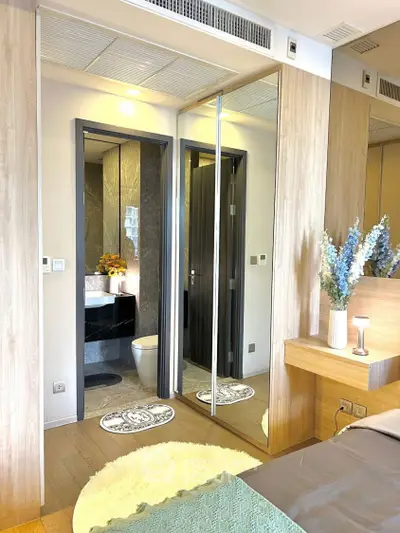 Modern bedroom with ensuite bathroom featuring elegant decor and mirrored closet doors.