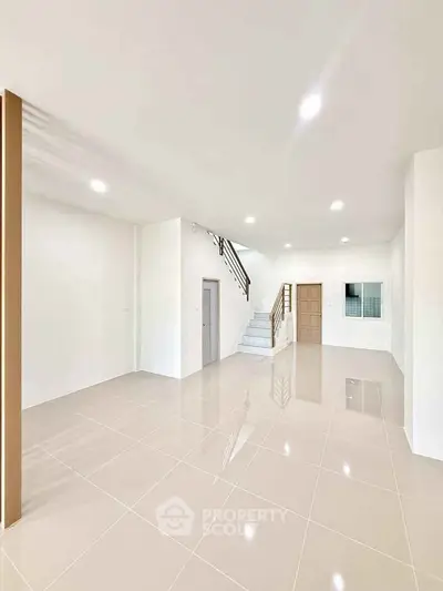 Spacious modern living room with glossy tiled floors and staircase, perfect for family gatherings.
