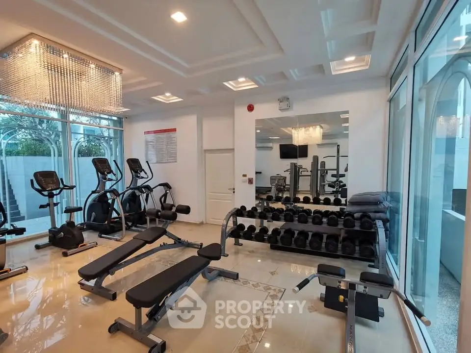 Luxurious gym with modern equipment and elegant lighting in upscale residential building.