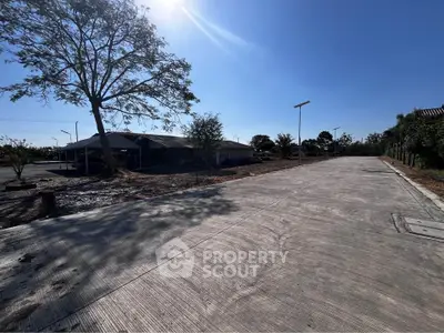 Spacious concrete driveway leading to a modern building under clear blue skies.