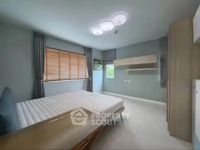 Spacious modern bedroom with large window and stylish lighting in a contemporary apartment.