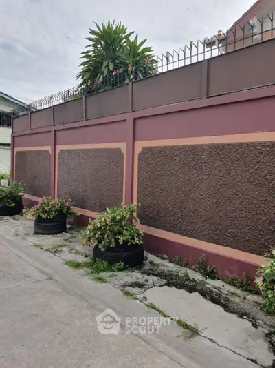 Charming exterior wall with lush greenery and decorative planters in a serene neighborhood setting.