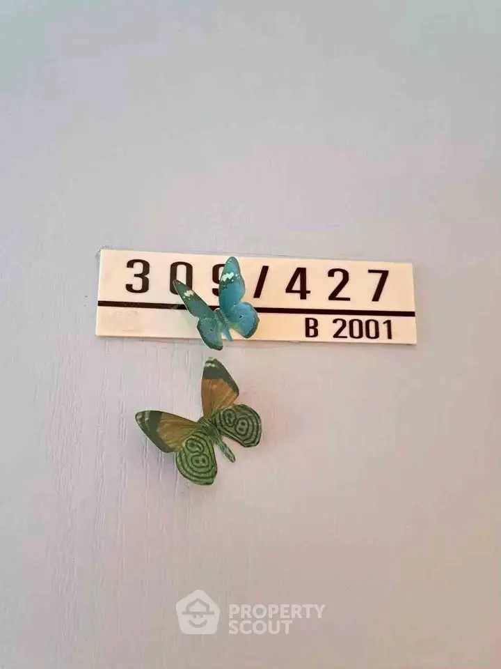 Charming apartment door number with decorative butterflies, adding a unique touch to the entrance.