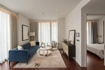 Modern living room with elegant decor and natural light, featuring a blue sofa and wooden flooring.