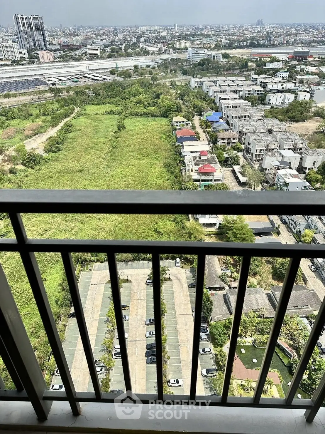 Stunning high-rise balcony view overlooking cityscape and greenery, perfect for urban living.