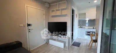 Modern living room with sleek TV setup and open kitchen layout in stylish apartment.
