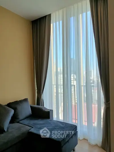 Cozy living room with large window and elegant curtains offering city view