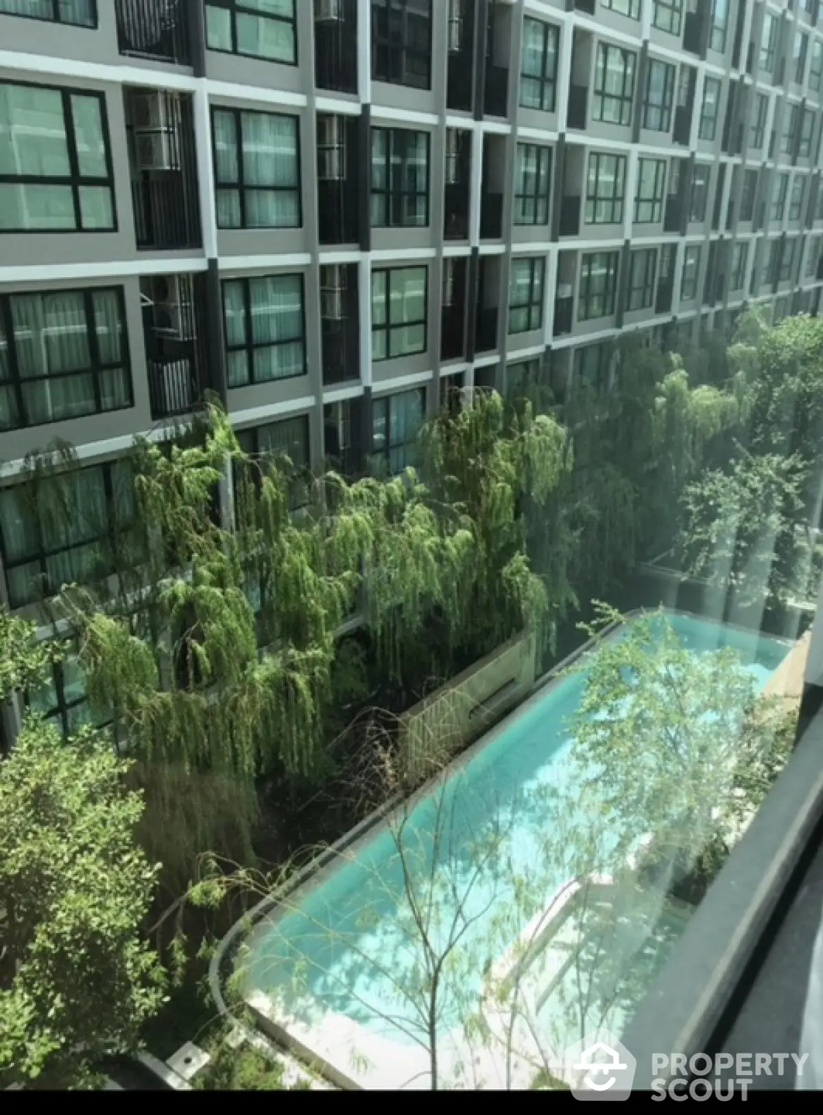 Modern apartment building with lush greenery and inviting swimming pool view.