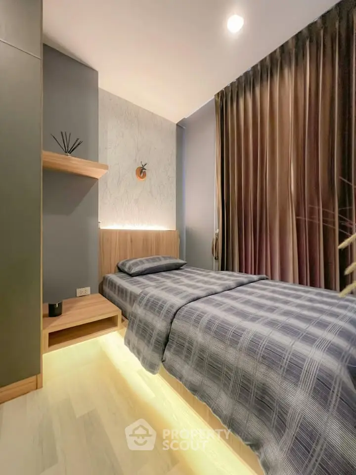 Modern bedroom with stylish decor and ambient lighting, featuring a cozy single bed and elegant curtains.