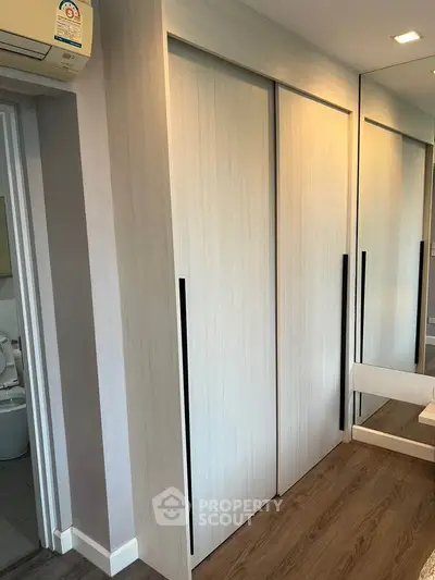 Modern bedroom with sleek sliding closet doors and mirrored accents