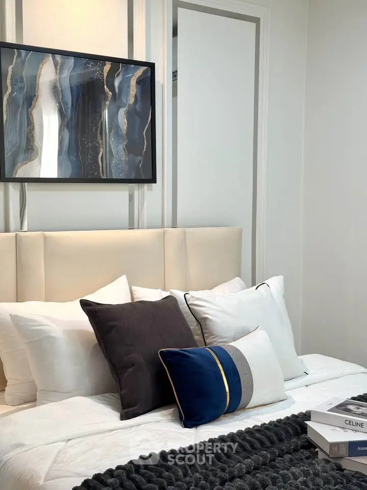 Elegant bedroom with modern art and plush pillows, perfect for relaxation.