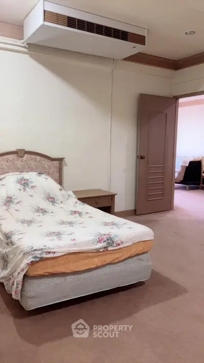 Cozy bedroom with floral bedding and open door to living area