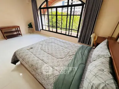 Spacious bedroom with large window and elegant decor in modern apartment