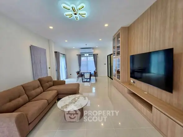 Spacious modern living room with elegant decor and large TV, perfect for relaxation.