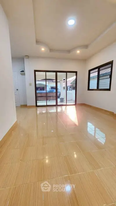 Spacious empty living room with large windows and glossy tiled floor