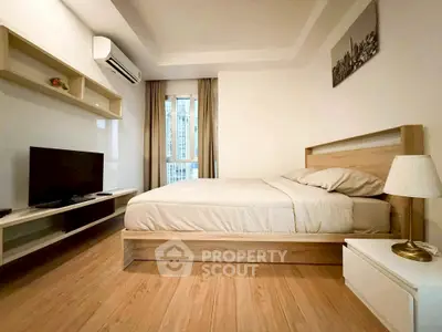 Modern bedroom with wooden flooring, cozy bed, and wall-mounted TV in a stylish apartment.