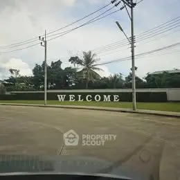 Welcome sign at the entrance of a residential community with lush greenery.
