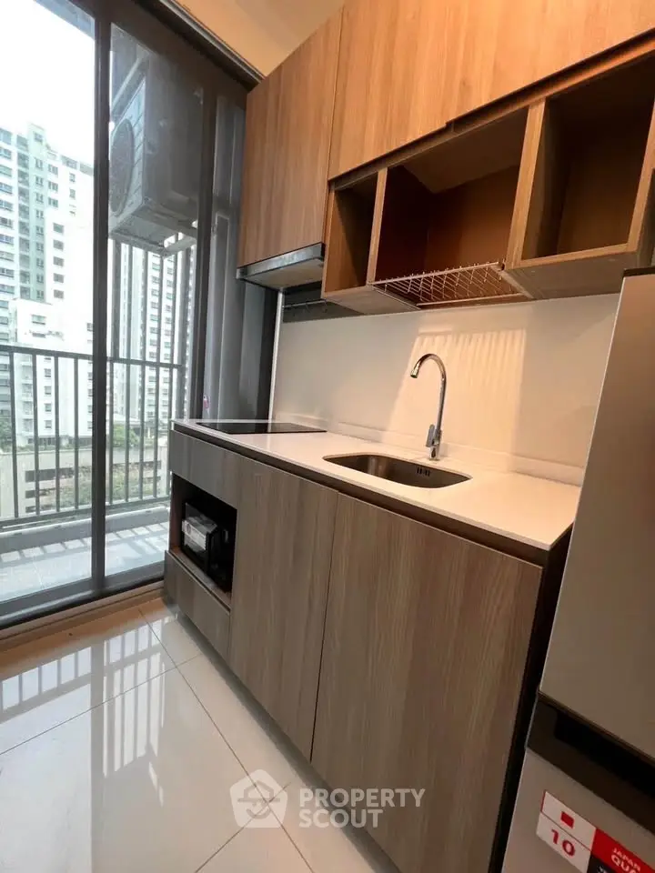 Modern kitchen with sleek cabinetry and balcony view in urban apartment