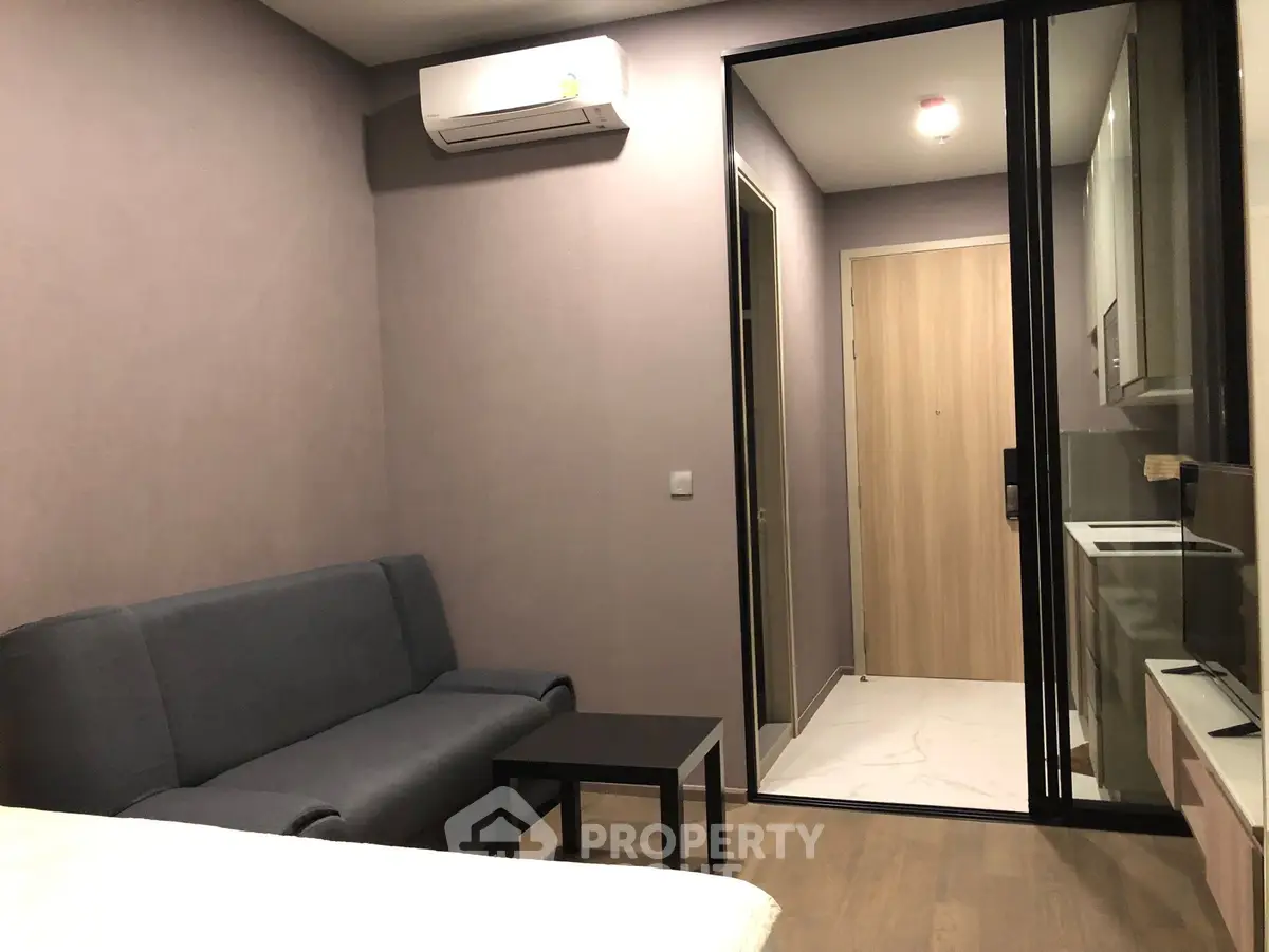 Modern studio apartment with compact living area and kitchenette, featuring sleek design and efficient use of space.