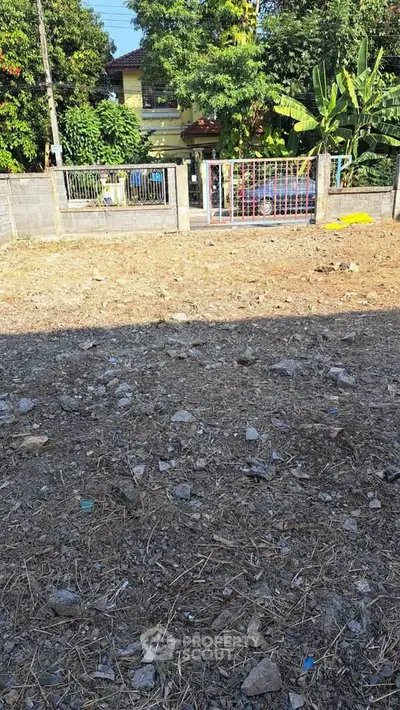 Vacant land plot with potential for development, surrounded by greenery and residential area.