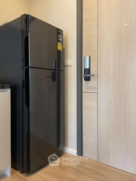 Modern kitchen with sleek black refrigerator and secure digital door lock