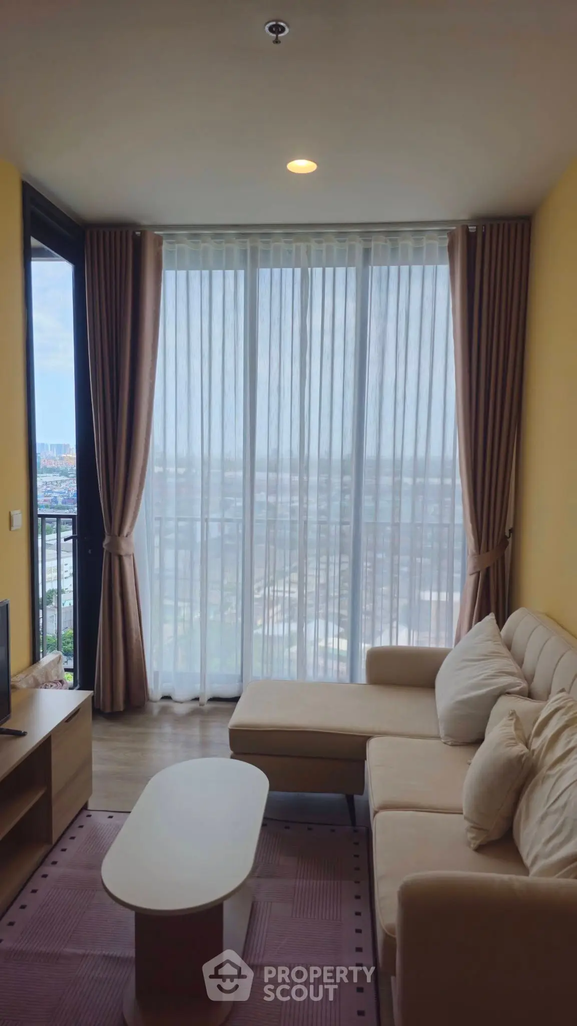 Bright living room with large windows and cozy sofa offering stunning city views.