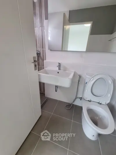 Modern bathroom with sleek fixtures and neutral tiles, featuring a compact design for efficient space use.