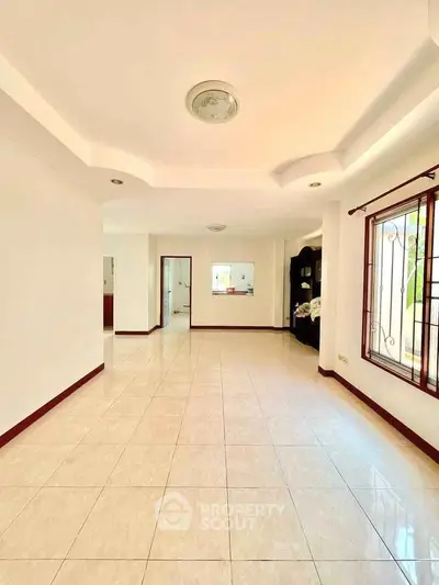 Spacious bright living room with large windows and elegant ceiling design.