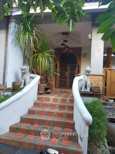 Charming entrance with decorative statues and lush greenery, perfect for a serene home ambiance.