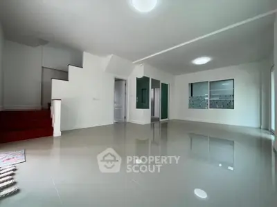 Spacious modern living room with glossy tile flooring and staircase