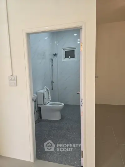 Modern bathroom with sleek white tiles and a contemporary toilet design, offering a clean and minimalist look.