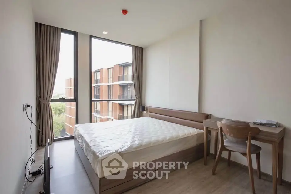Modern bedroom with large windows and natural light in a contemporary apartment.