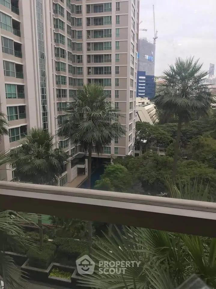 Stunning view from a high-rise apartment overlooking lush greenery and modern architecture.