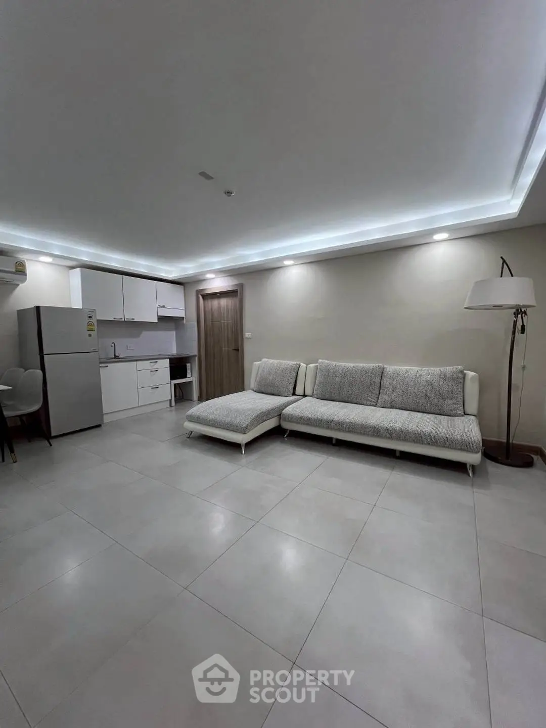 Modern living room with sleek kitchen and stylish furniture in open layout.