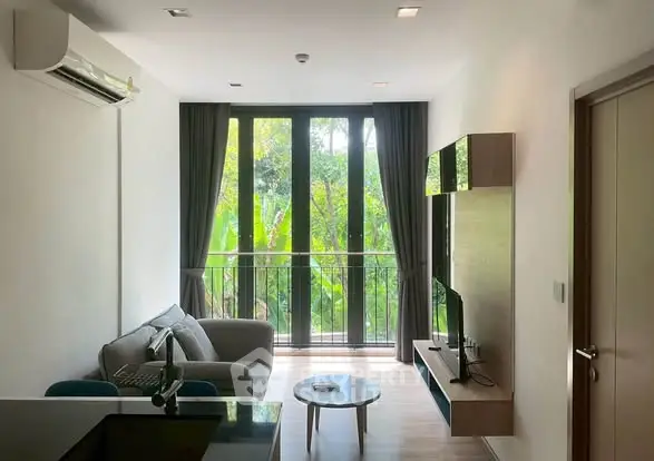 Modern living room with large windows and lush garden view, featuring sleek furniture and natural light.