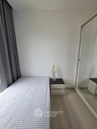 Minimalist bedroom with mirrored wardrobe and bedside table in modern apartment.
