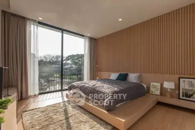 Luxurious bedroom with large windows and modern decor, offering a serene view and ample natural light.