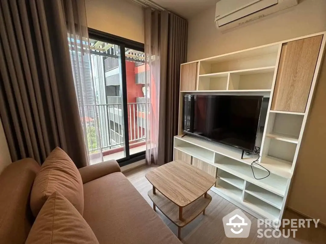 Cozy living room with modern furniture, large windows, and access to a sunny balcony, perfect for urban living and relaxation.